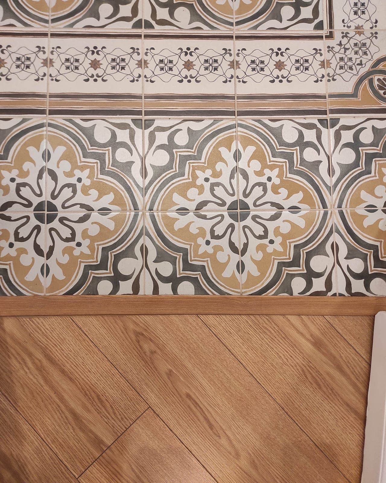 Patterned tiles meeting the oak floor
